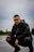man in black jacket and black pants sitting on road during daytime