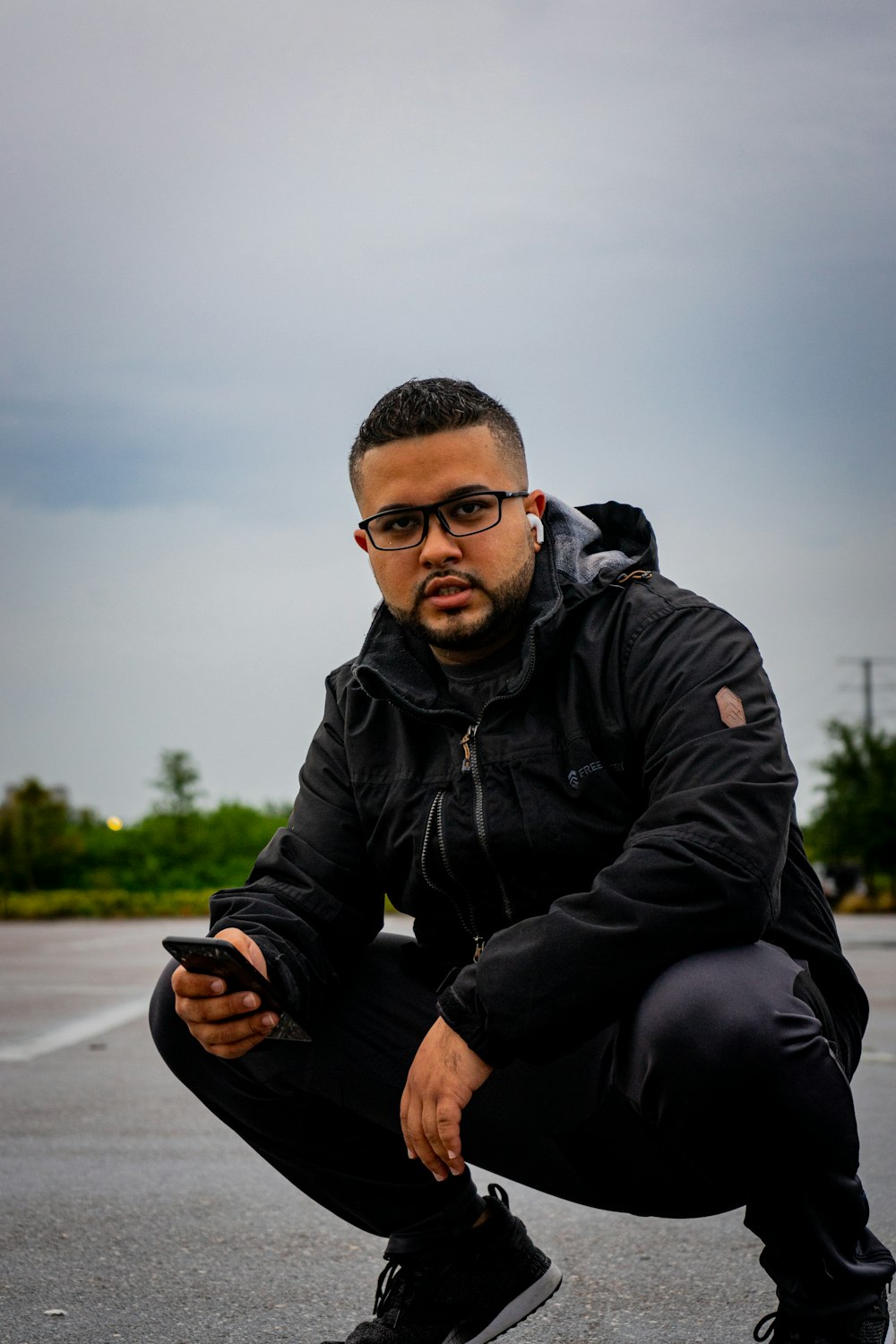 man in black jacket and black pants sitting on road during daytime