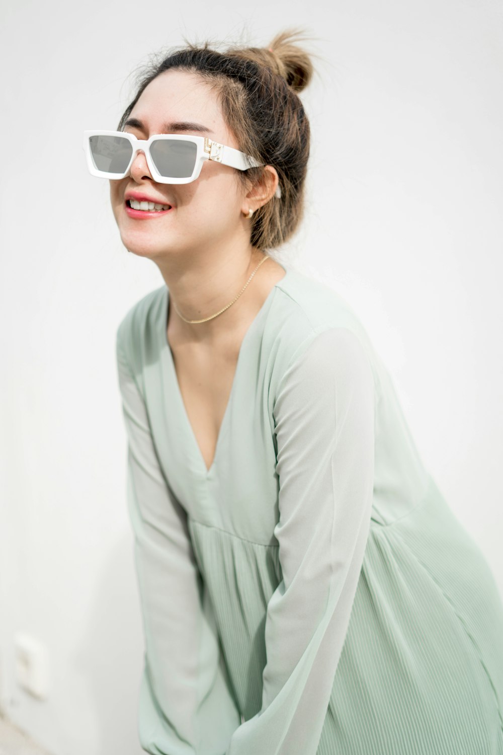 woman in teal v neck long sleeve shirt wearing white framed sunglasses