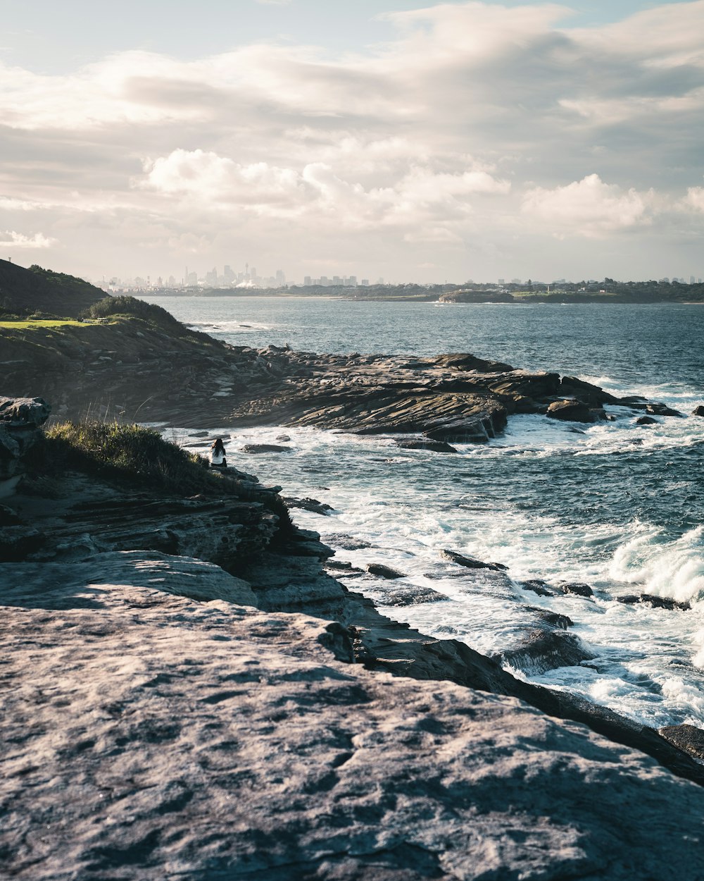 brown rock formation on sea under white clouds during daytime