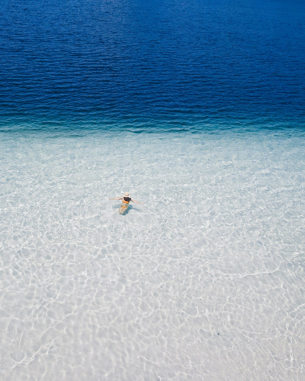 Persona in camicia bianca e pantaloncini neri che cammina sulla spiaggia durante il giorno