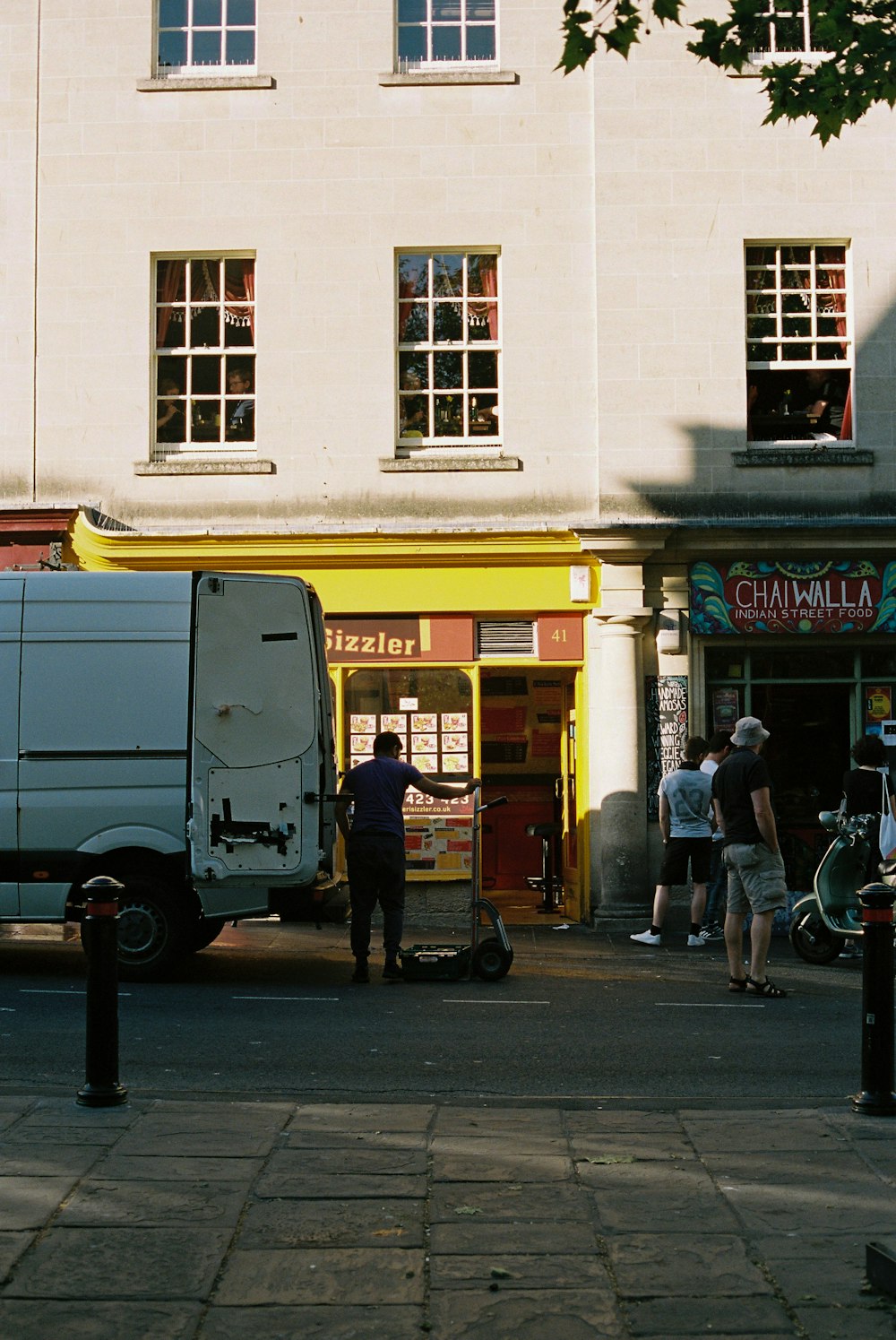 man in black jacket and blue denim jeans standing beside white van during daytime