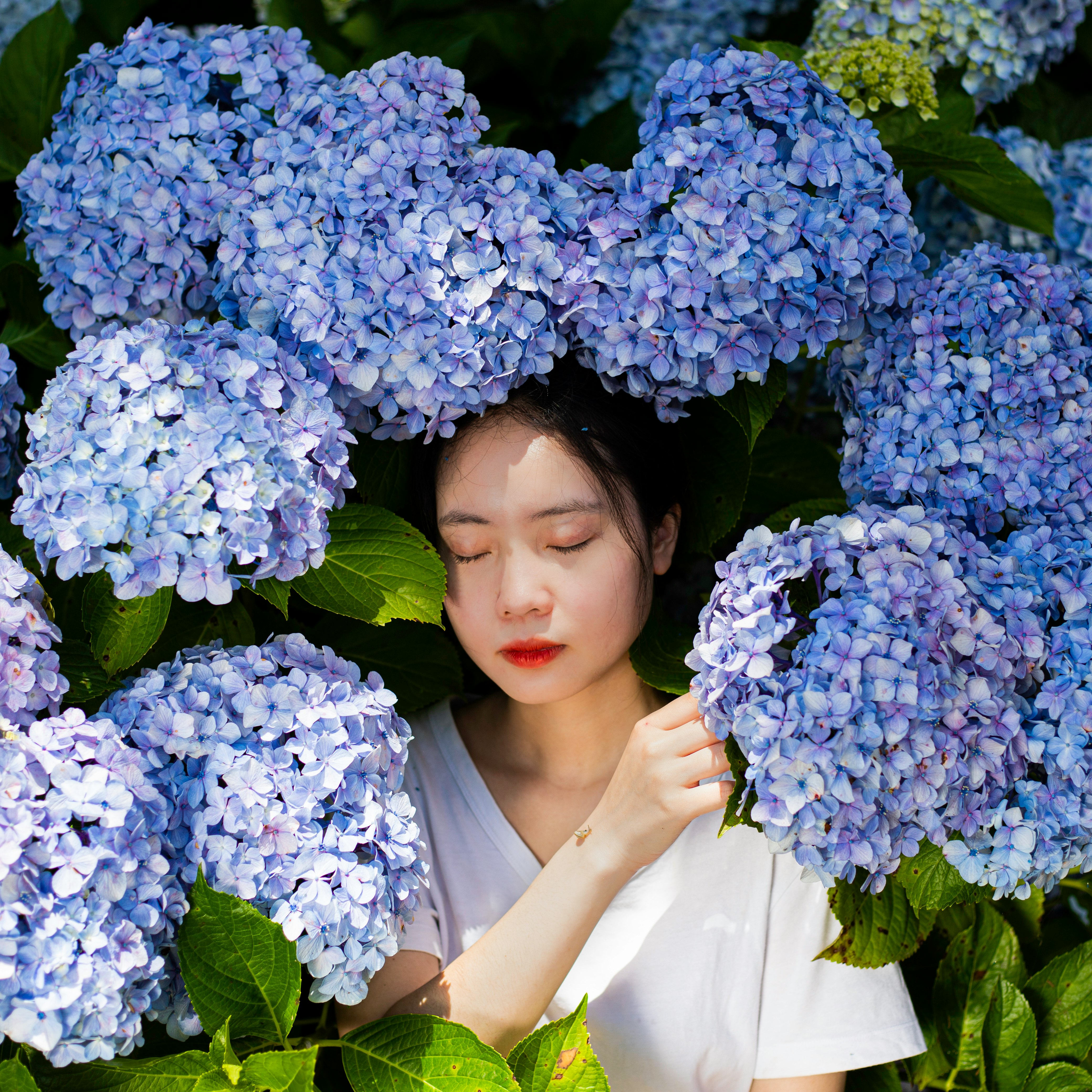 woman in white dress holding blue flowers