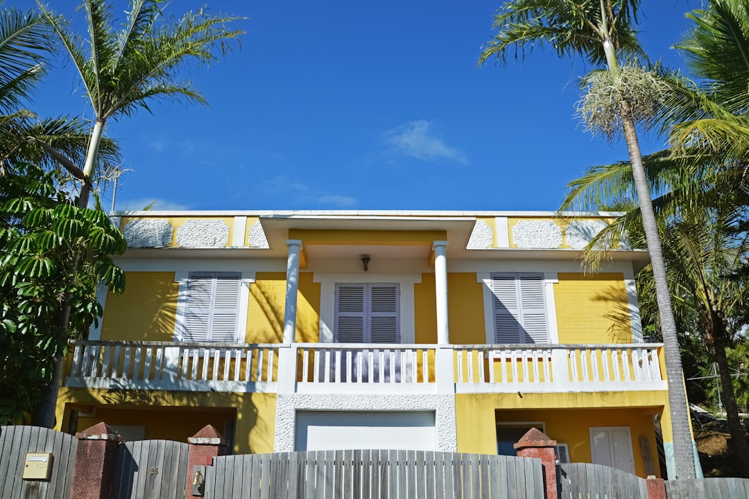 white concrete house near palm tree under blue sky during daytime