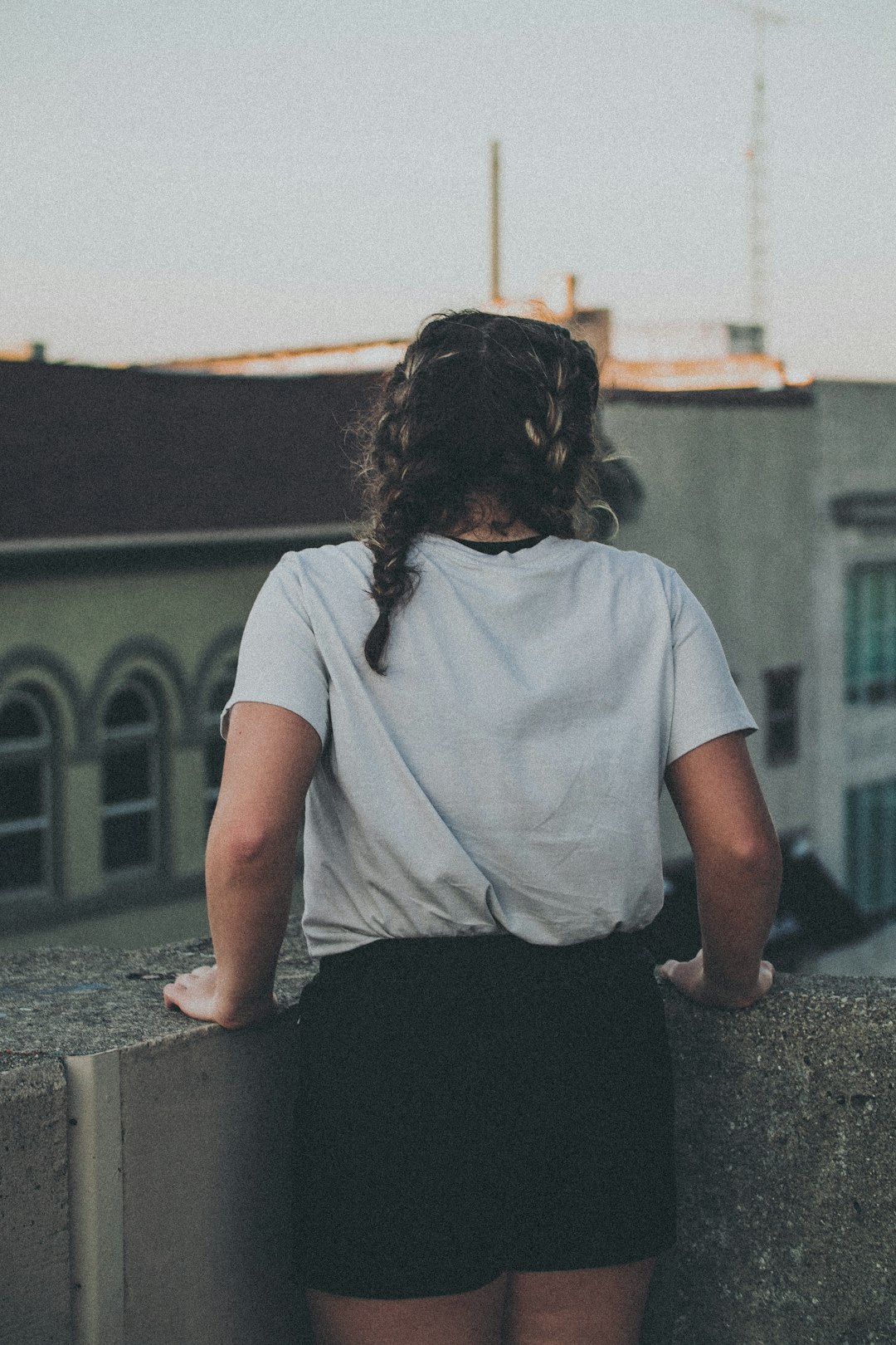 woman in white t-shirt and black pants sitting on concrete bench during daytime