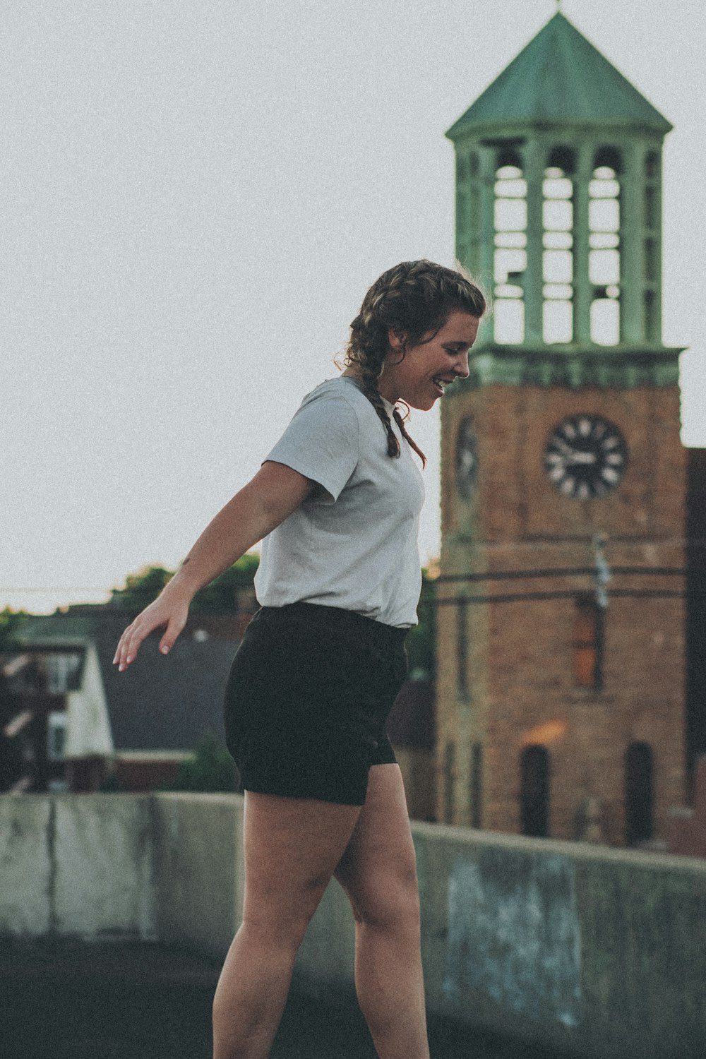 woman in white shirt and black shorts standing on gray concrete pavement during daytime