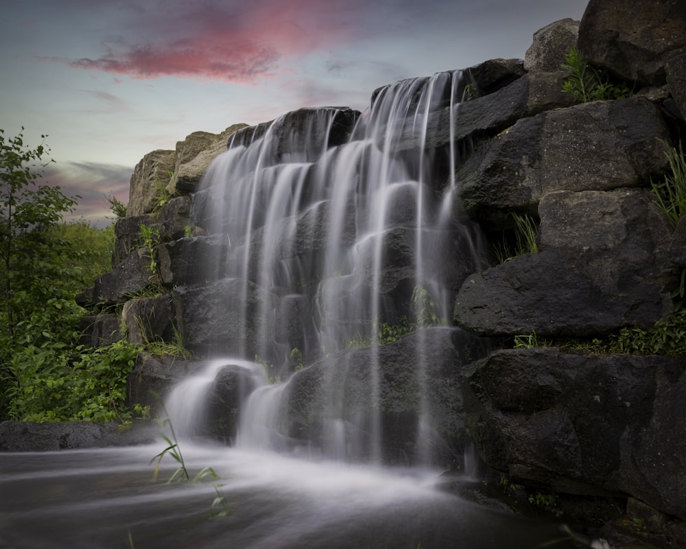 water falls on gray rocky mountain during daytime