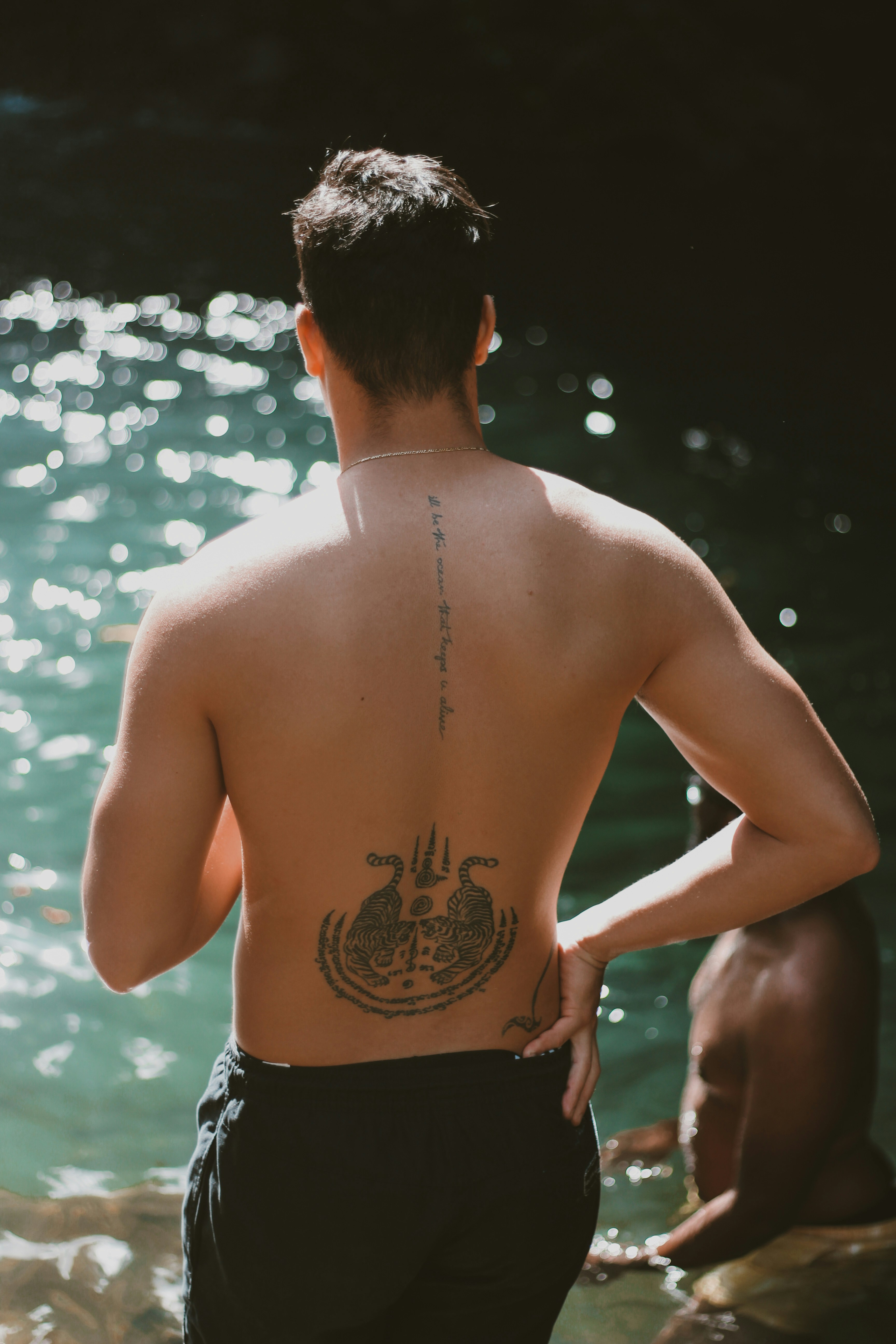 topless man with tattoo on back