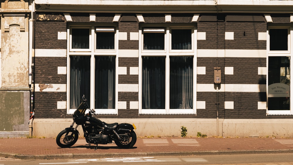 black motorcycle parked beside white and brown concrete building during daytime
