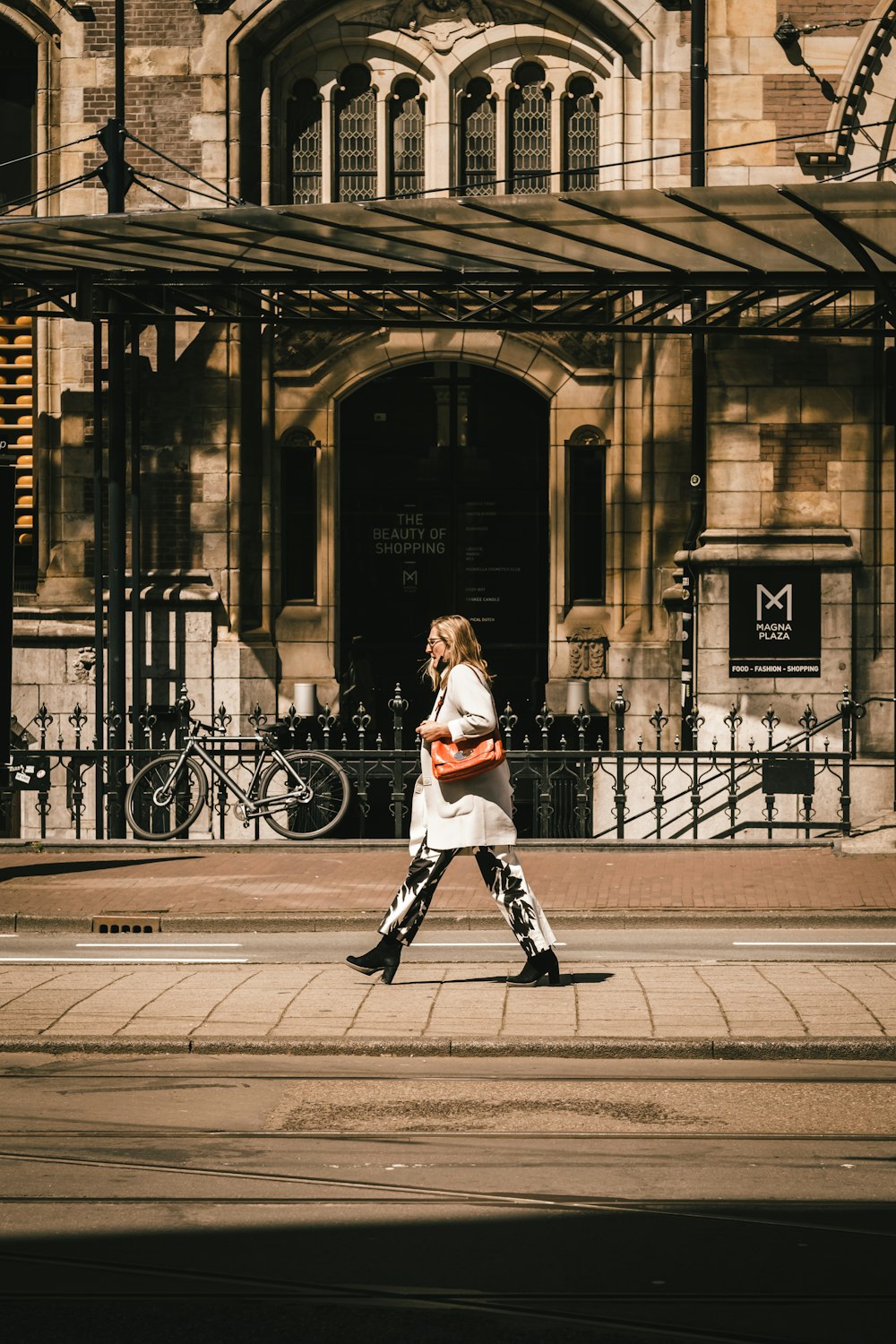 woman in white long sleeve shirt and black pants walking on sidewalk during daytime