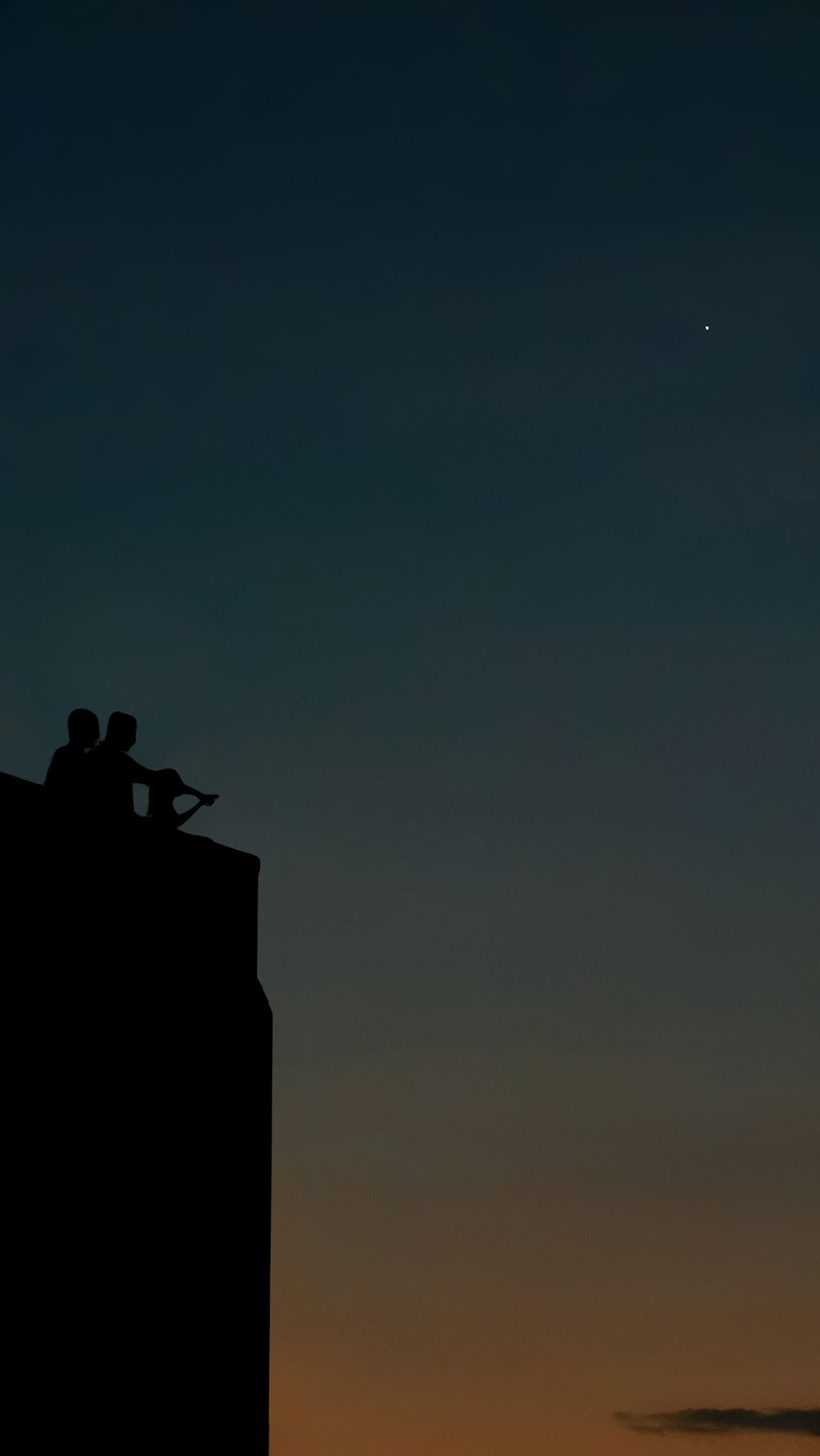 silhouette of man sitting on building