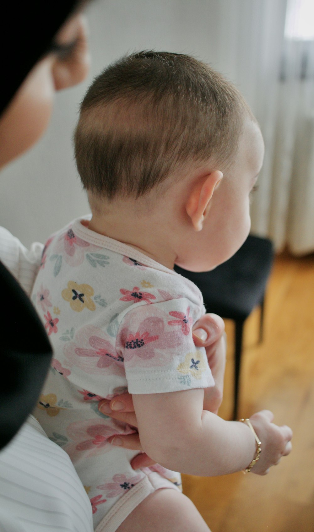 child in white and pink floral shirt sitting on black chair