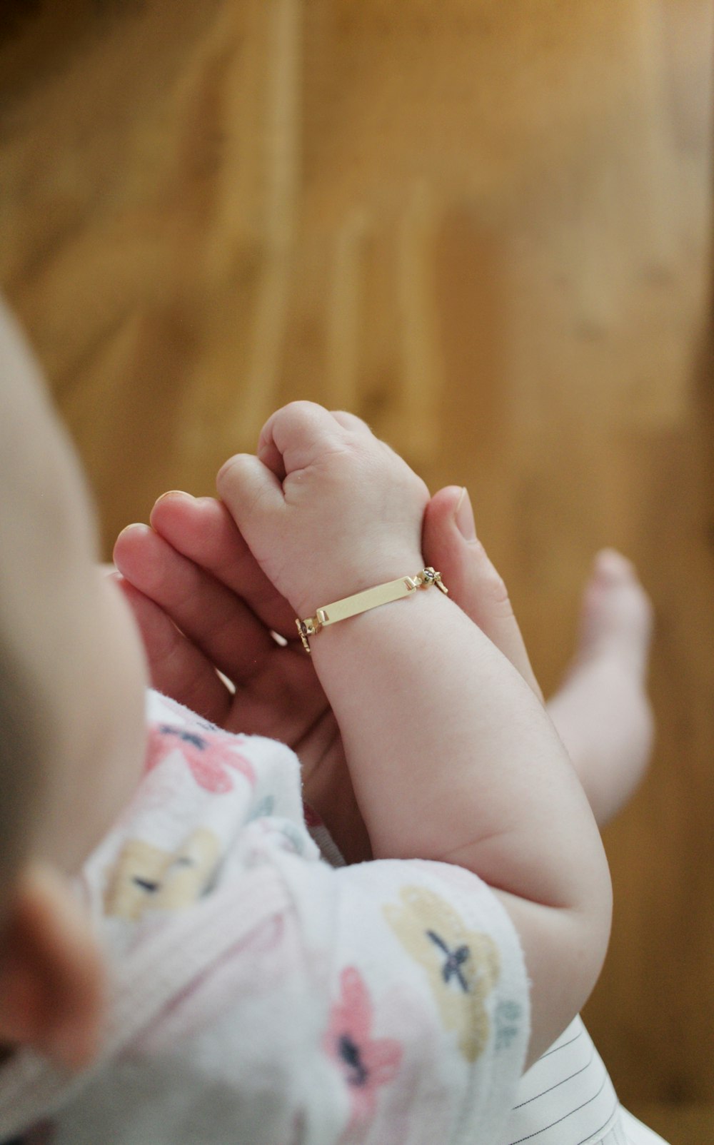 person wearing gold ring holding babys foot