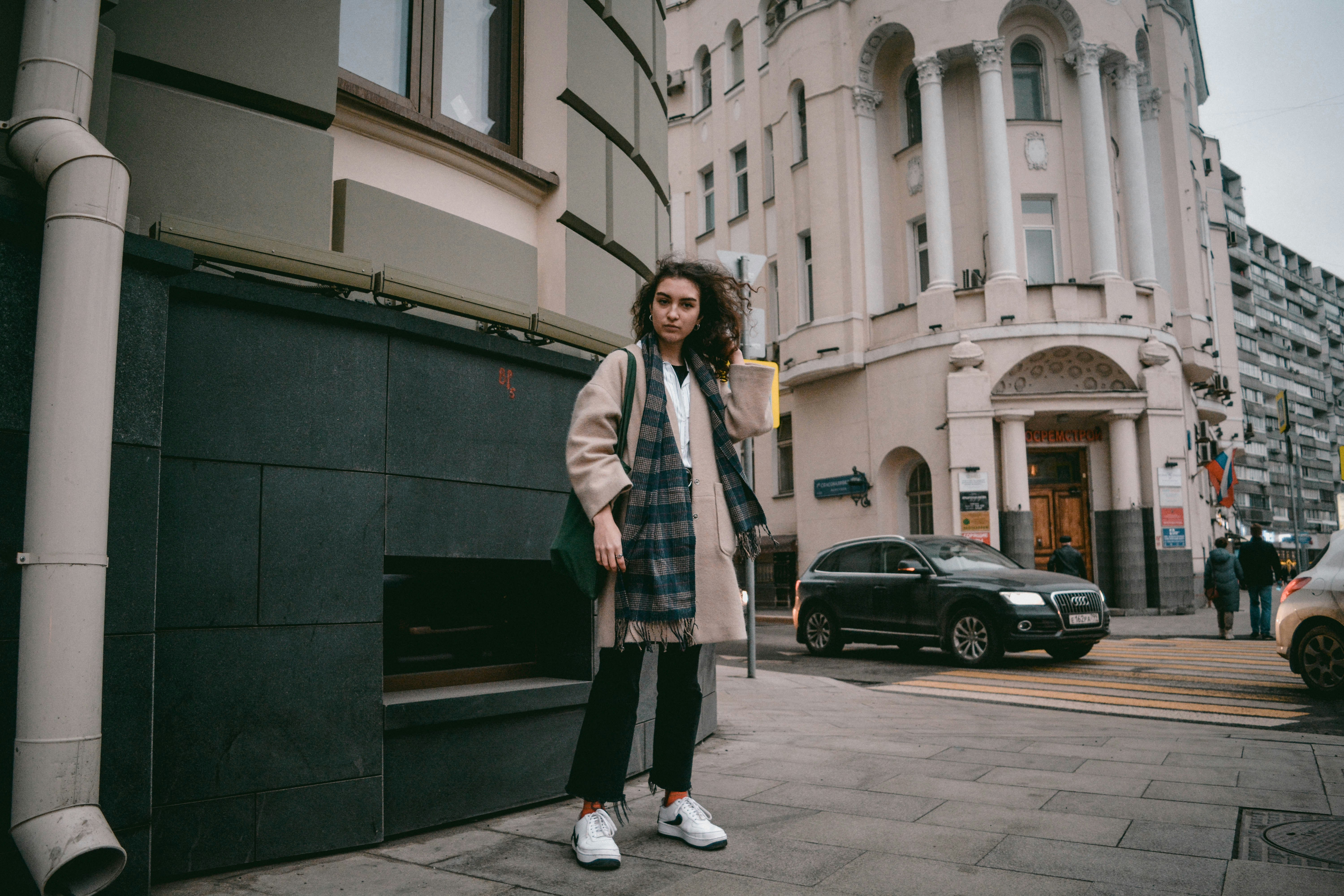 woman in black and white plaid coat standing on sidewalk during daytime