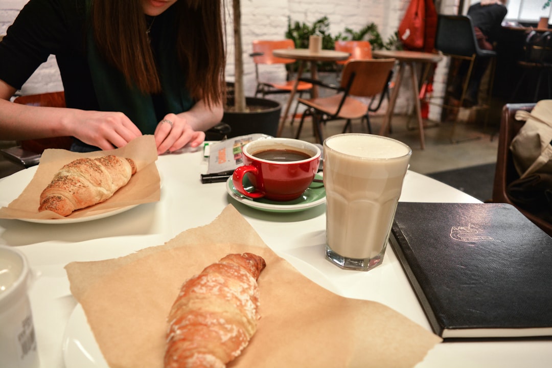person in black shirt sitting at table with bread and cup of coffee