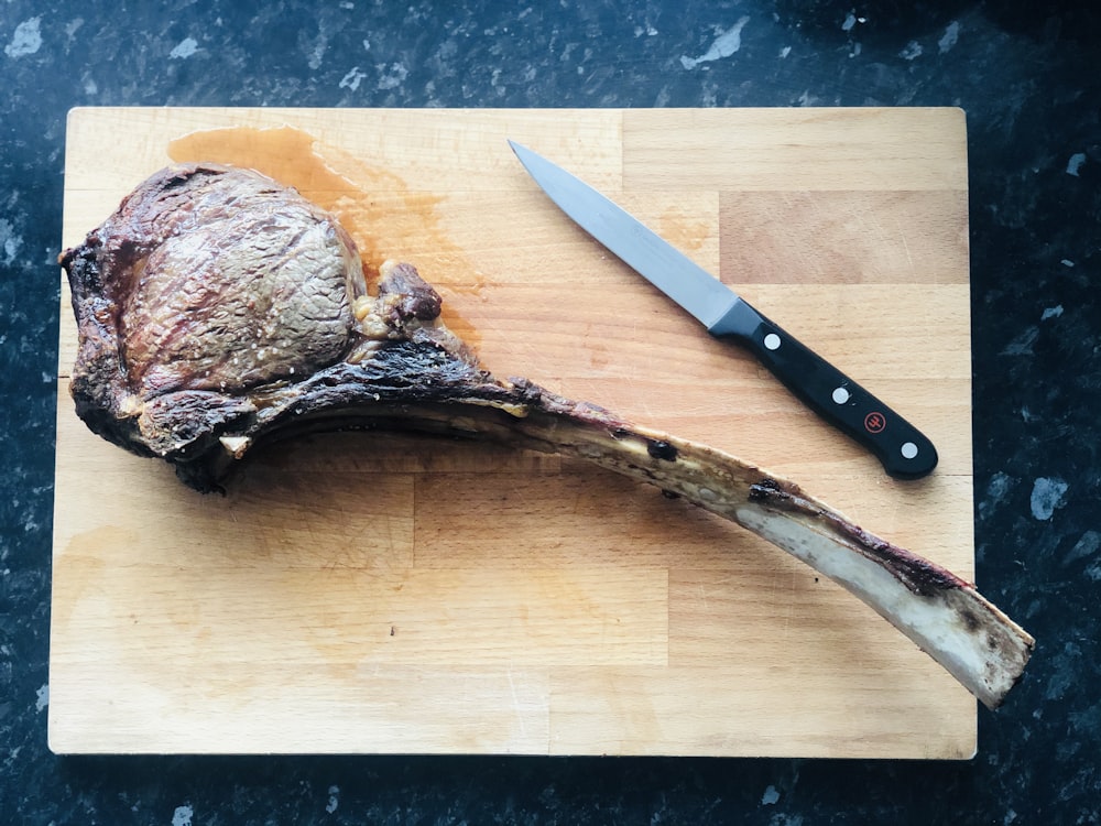 cuchillo con mango de madera marrón en tabla de cortar de madera marrón