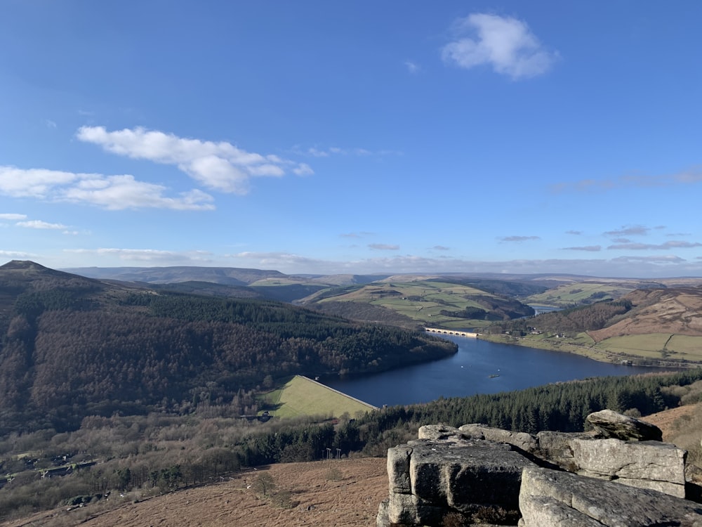 Grüne Bäume und Berge in der Nähe des Sees unter blauem Himmel tagsüber