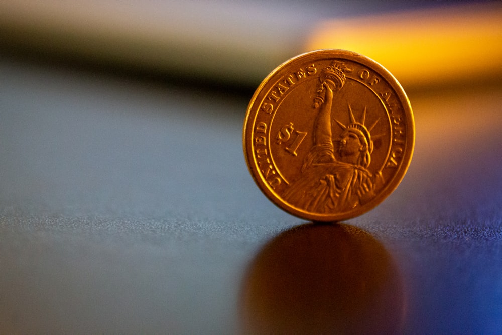 gold round coin on white surface