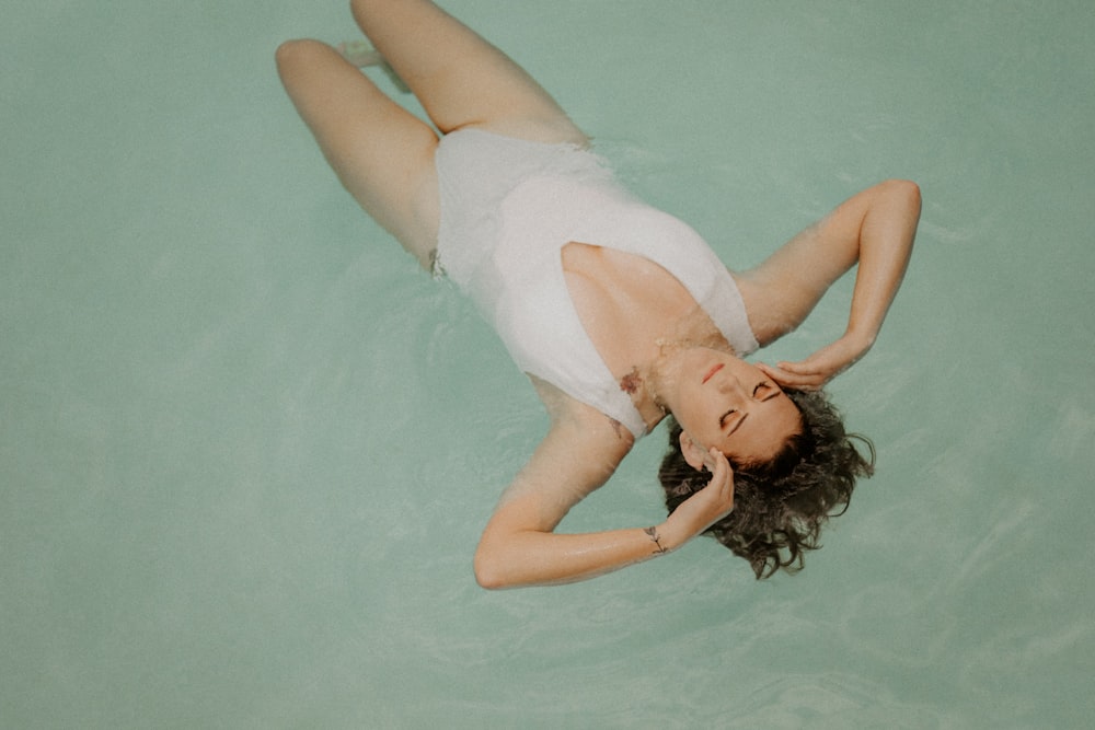 woman in white tank top lying on water