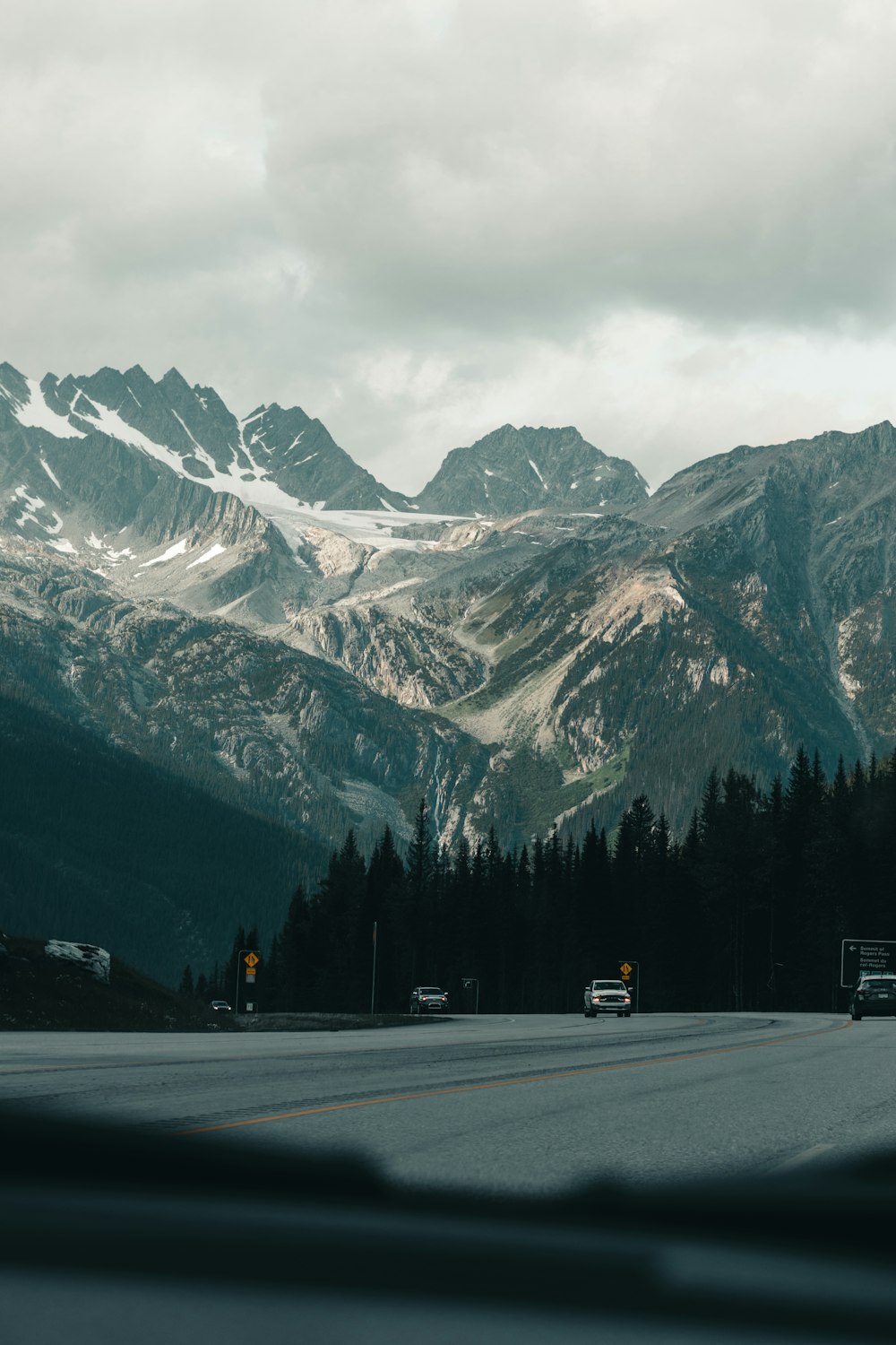 estrada de asfalto cinza perto da montanha coberta de neve durante o dia