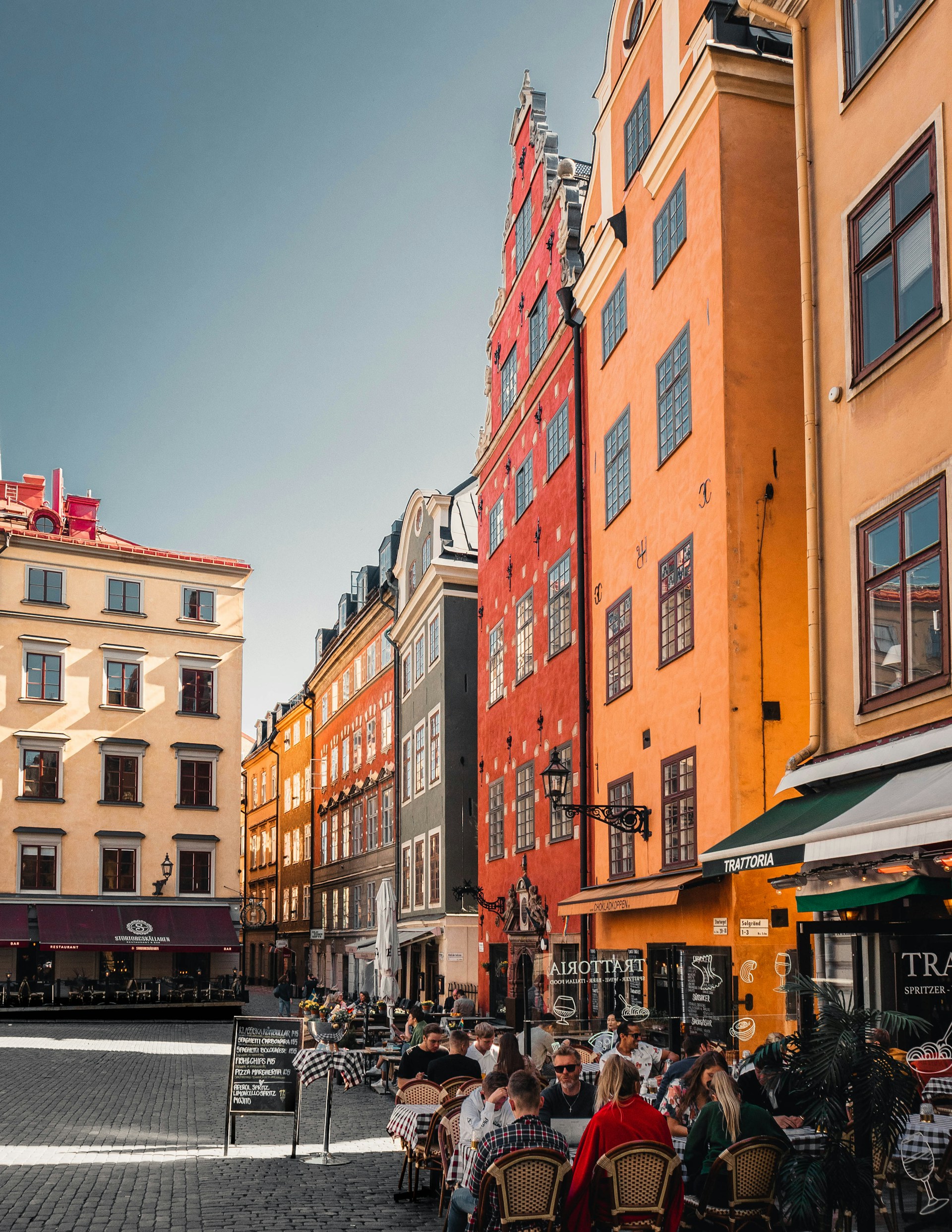 A vibrant street scene capturing locals enjoying a sunny afternoon at Prato della Valle, with historic buildings framing the lively square.