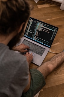 person using macbook pro on brown wooden table