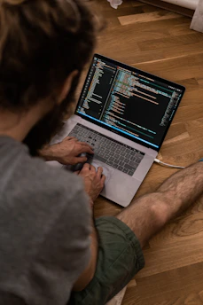 person using macbook pro on brown wooden table