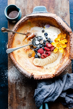 Close-up of a golden Dutch baby pancake topped with fresh berries and powdered sugar.