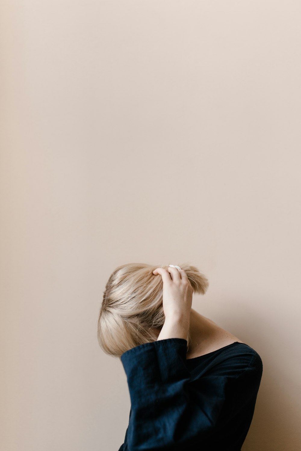 woman in blue shirt covering her face with her hair