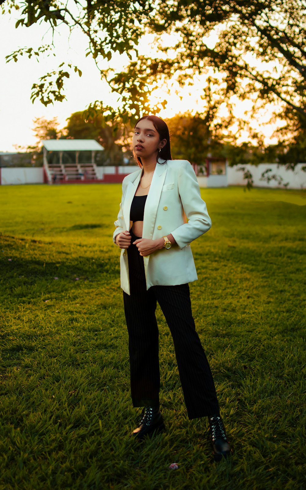 woman in white blazer standing on green grass field during daytime