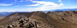 A panoramic view of a rugged trail winding through rocky terrain under a clear blue sky