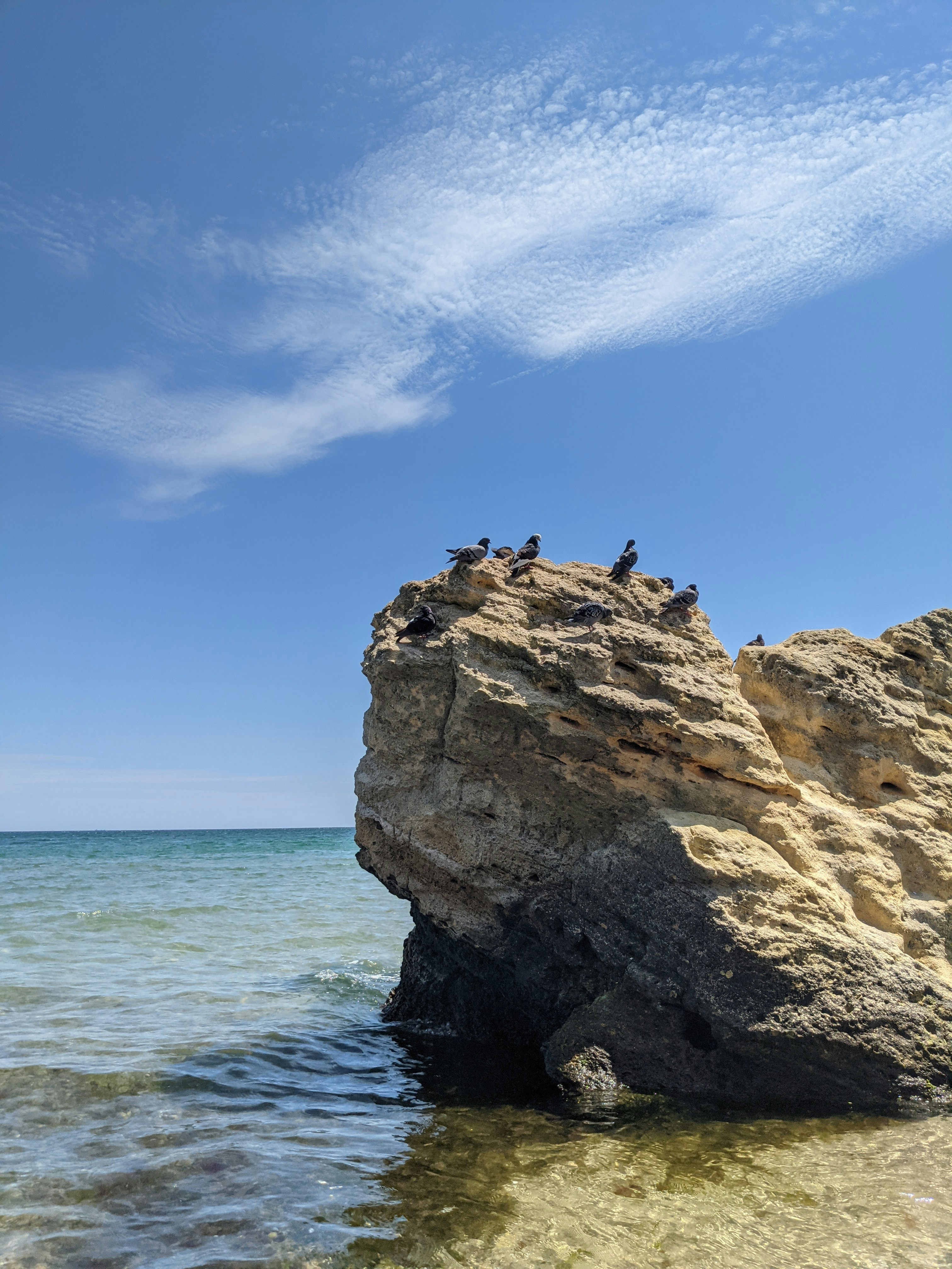 brown rock formation on sea under blue sky during daytime