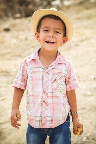 A cheerful child wearing a handmade cotton hat, smiling outdoors.