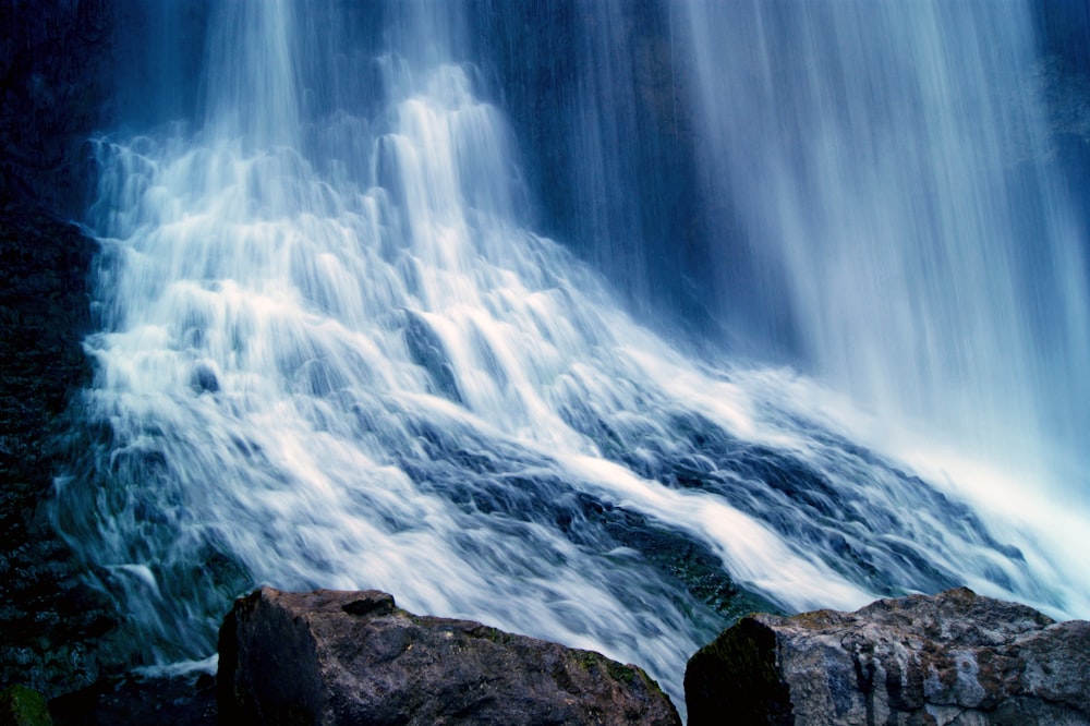 water falls on rocky shore during daytime