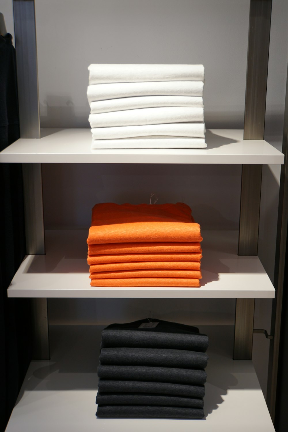 weiße und orangefarbene Handtücher auf weißem Holzregal