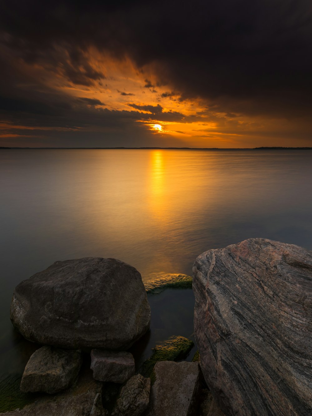 gray rock formation near body of water during sunset