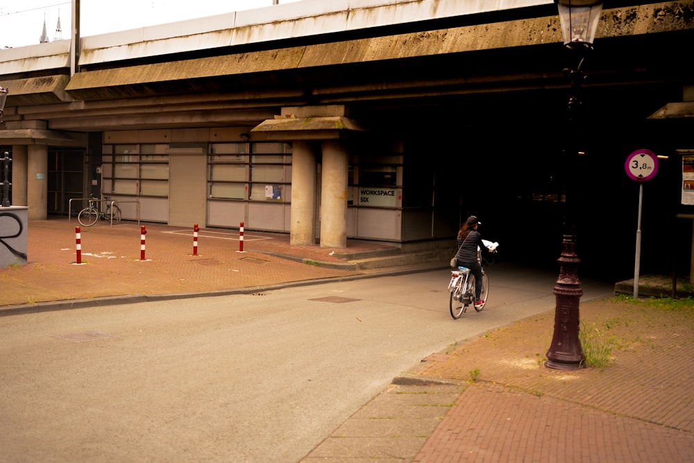 man in black jacket riding bicycle on gray concrete road during daytime