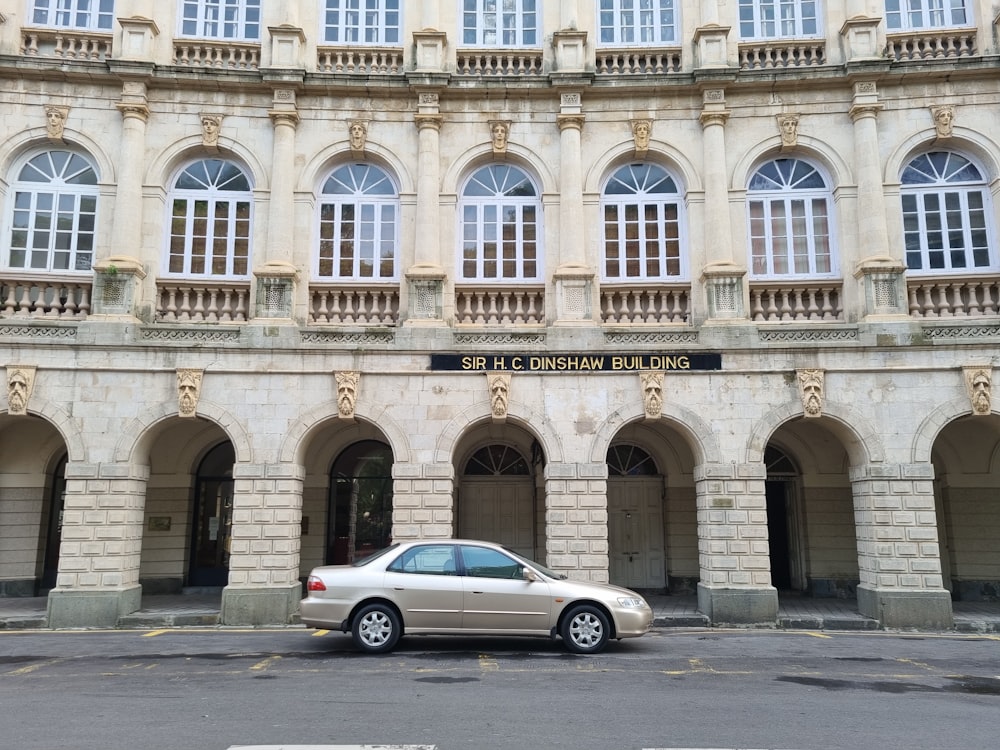 silver sedan parked in front of beige concrete building during daytime