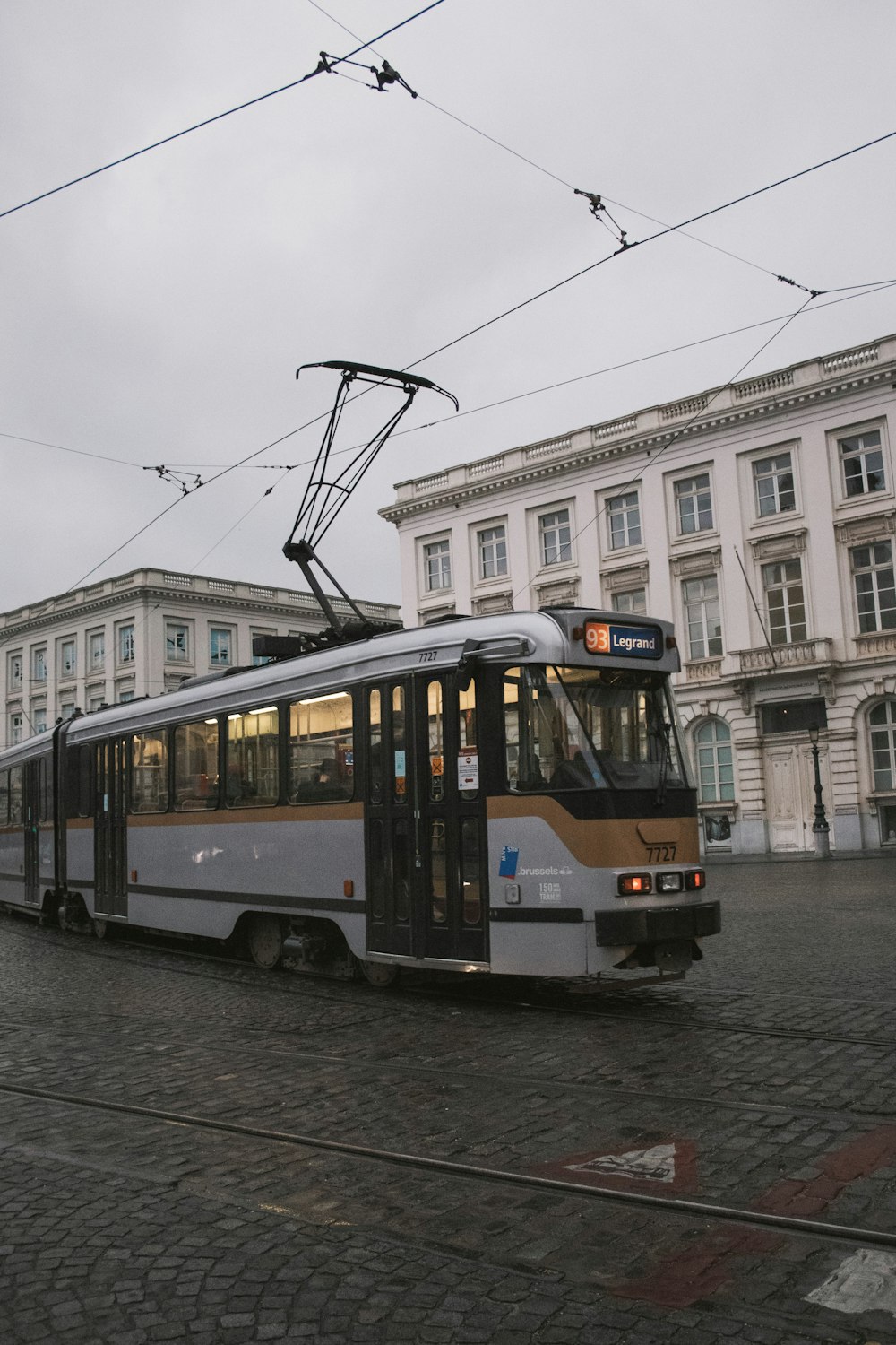 white and black tram on road near white concrete building during daytime