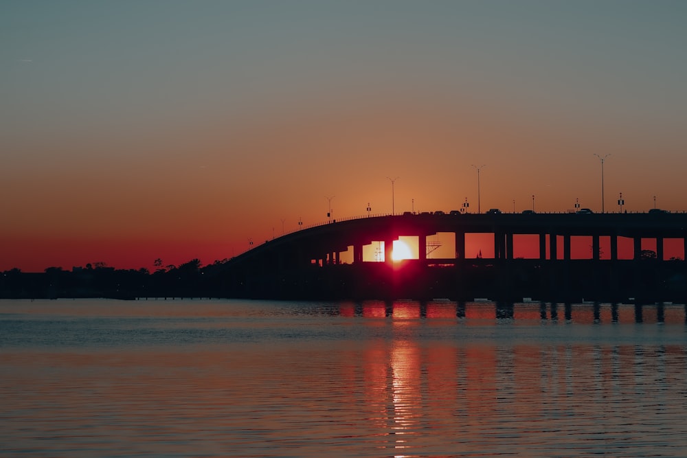 Silhouette der Brücke über das Gewässer bei Sonnenuntergang