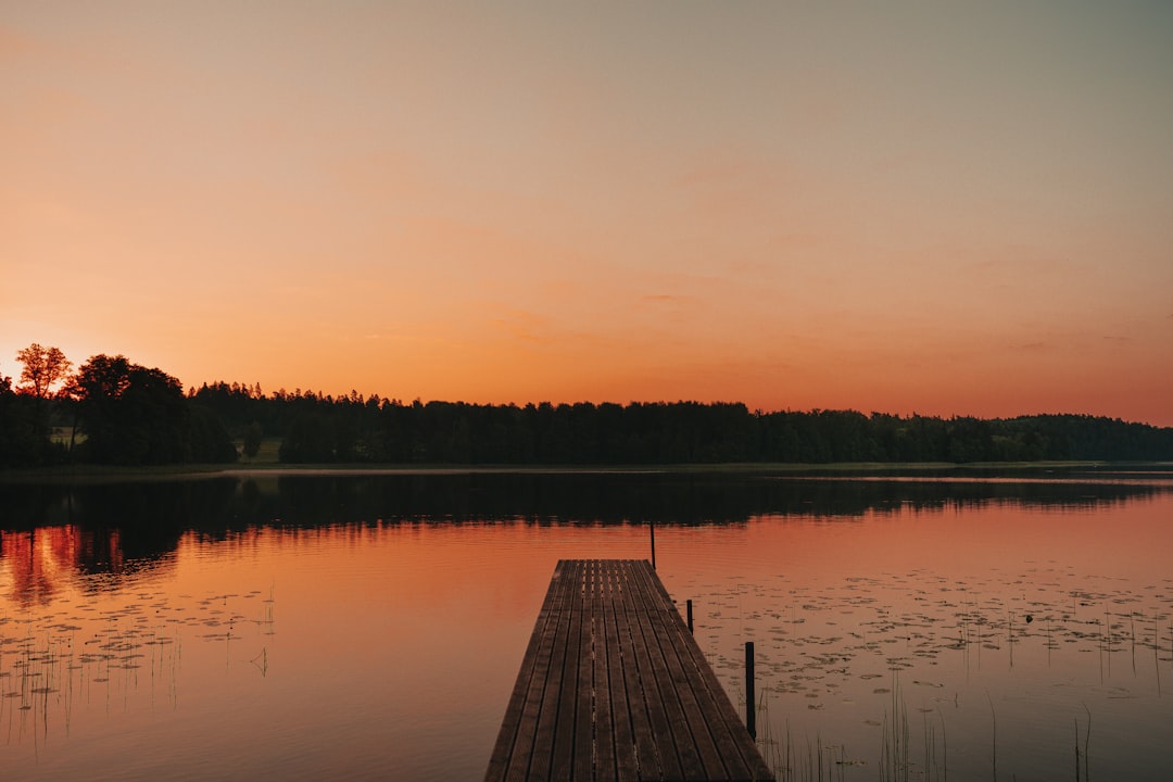 brown wooden dock on lake during sunset
