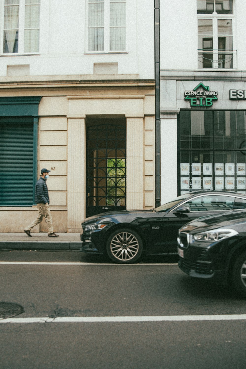 man in black jacket and pants standing beside black car during daytime