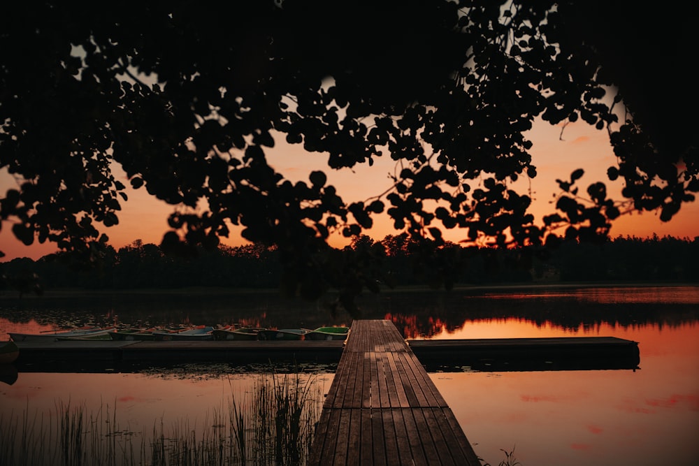 brown wooden dock on lake during sunset