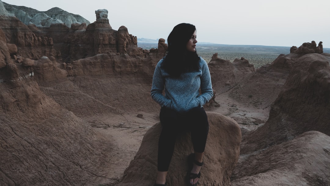 woman in blue and white floral long sleeve shirt and black pants standing on brown rock