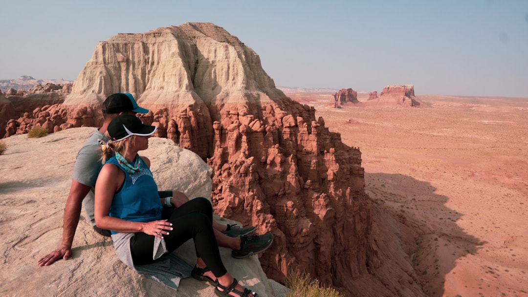 man in blue shirt and black pants sitting on rock formation during daytime