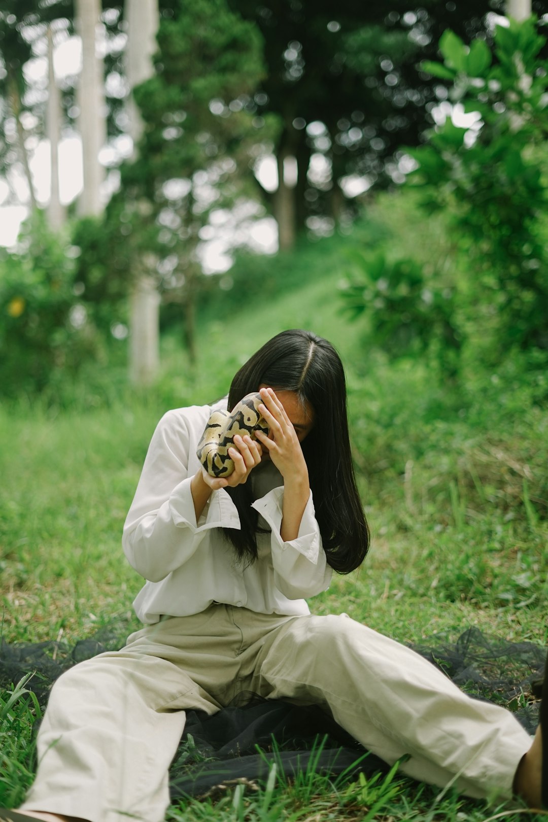 woman in white robe sitting on green grass field during daytime