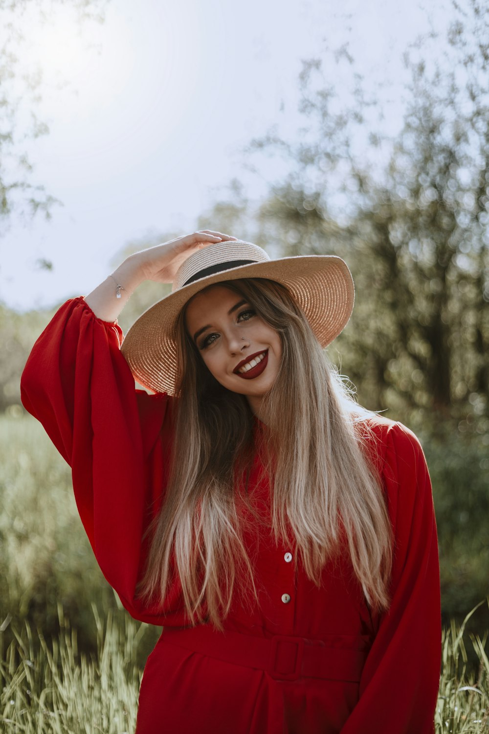 woman in red long sleeve shirt wearing brown fedora hat