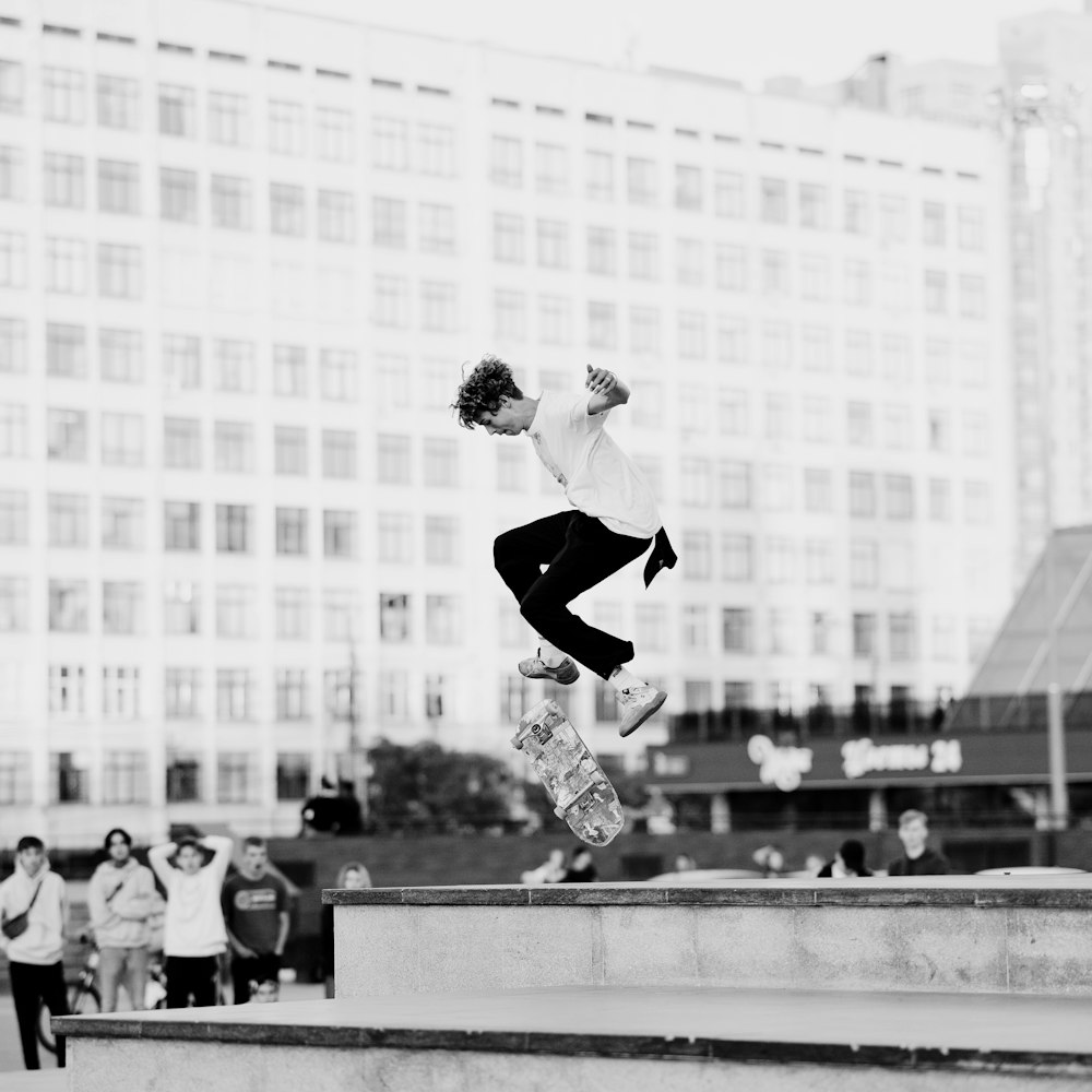 man in black jacket and pants jumping on the field in grayscale photography