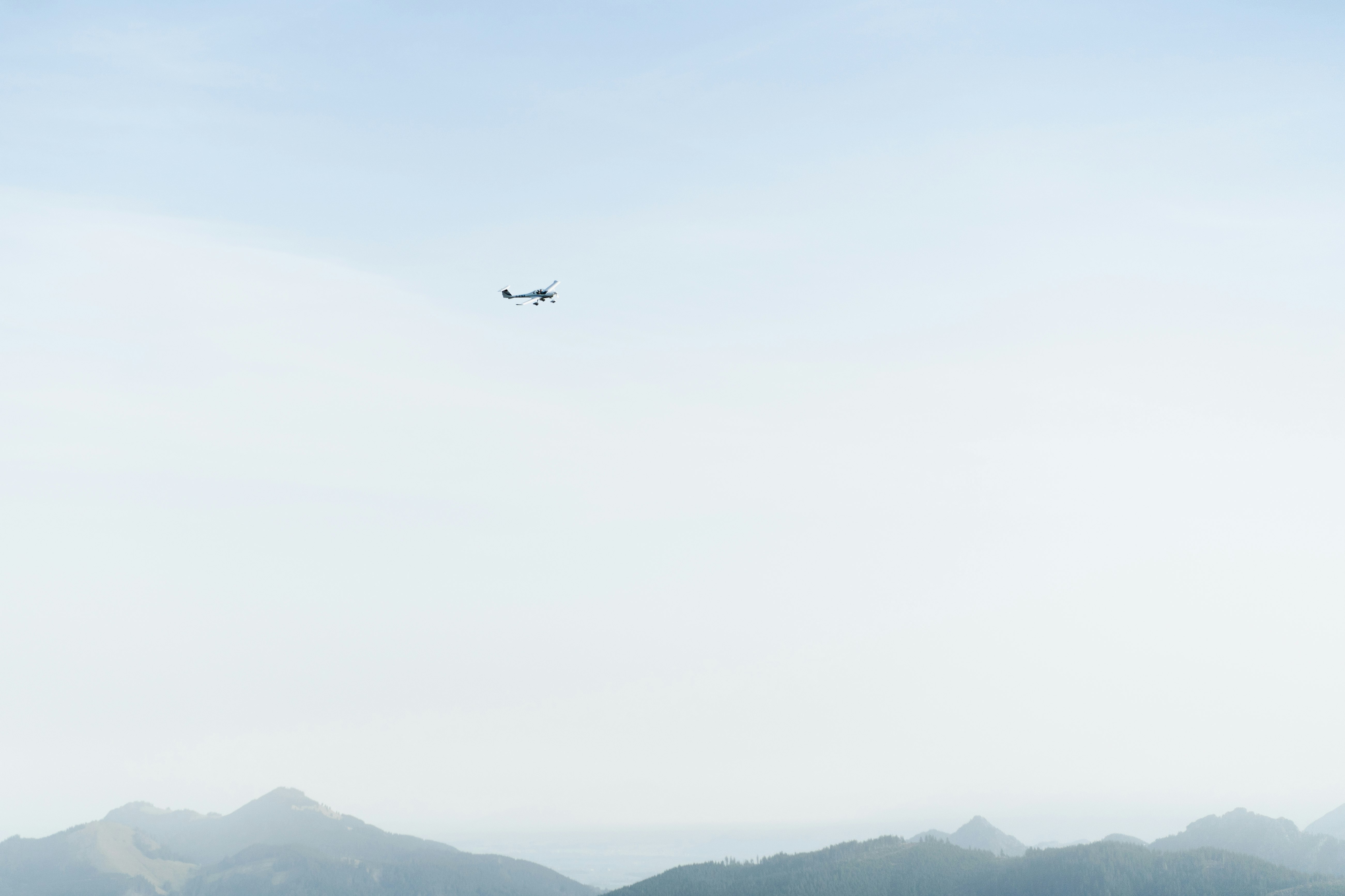 black airplane flying over the mountains during daytime