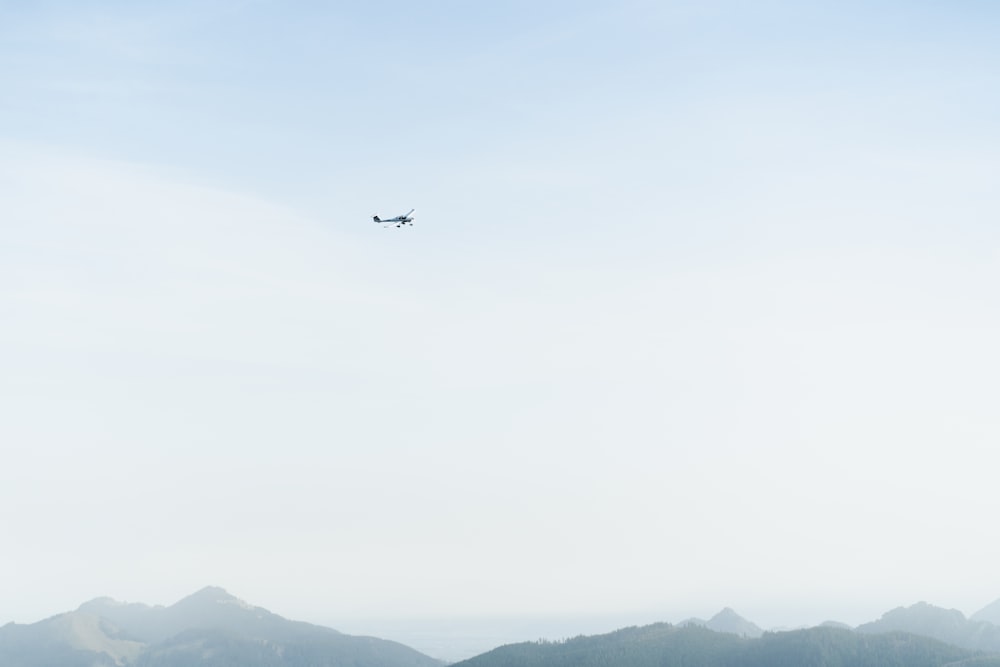 black airplane flying over the mountains during daytime